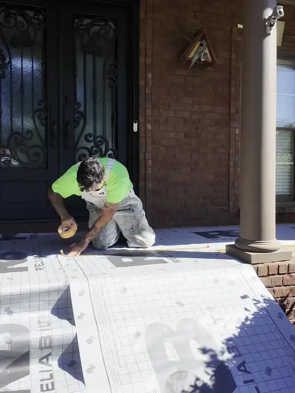 A Hisway painter masking the porch steps before an exterior paint job